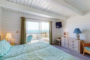 Ein Schlafzimmer mit Bett, Schminktisch, Stuhl, Fernseher und einem Balkon mit Blick.