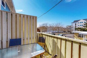 Ein Balkon mit Tisch und Stühlen, ein Holzzaun und Blick auf Gebäude sowie einen Parkplatz.