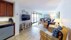 Eine moderne Küche mit Geschirrspüler, Flachbildfernseher und Essbereich mit Rattanmöbeln.