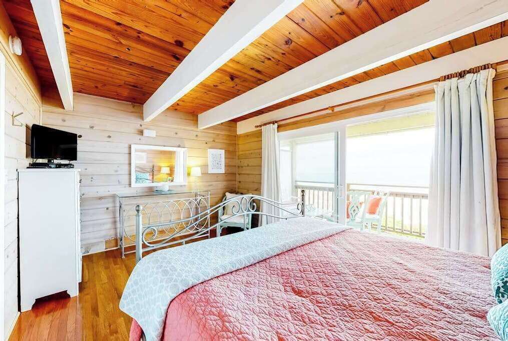 Ein Zimmer mit Holzwänden, einem Bett, einem Schreibtisch und einem Fernseher.