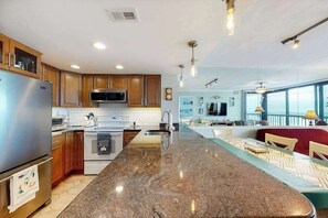 A modern kitchen with granite countertops, stainless steel appliances, and wooden cabinets. - Ocean-view condo with balcony, pools, tennis, gym & saunas (Ocean City)