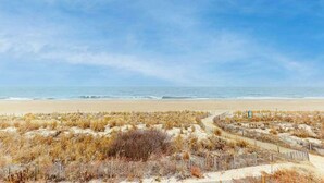 Une plage bordée d’une clôture en bois et où la végétation est sèche.
