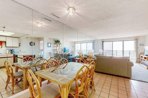 A spacious living area with a dining table, chairs, and a sofa. - Oceanfront Condo w/ Balcony, Ocean View, Central AC, W/D & Beach Access (Ocean City)