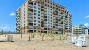 Een hotel met meerdere verdiepingen en balkons, nabij een zandstrand.