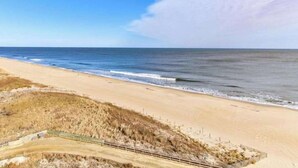 Een strand met een zandstrand, een houten loofpad en duinen op de voorgrond.