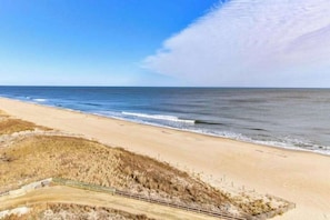 A beach with a sandy shore, a wooden boardwalk, and dunes in the foreground. - Sandpiper Dunes 808 (Ocean City)