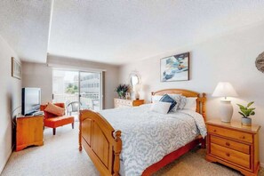A bedroom with a bed, bedside table, lamp, and a television on a stand. - Inviting Beach Condo w/Private Balcony, Great Location, Washer/Dryer, Central AC (Ocean City)