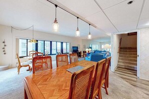 A spacious living area with a wooden herringbone dining table, wicker chairs, and pendant lighting. - Terrific Ocean View Condo w/Private W/D, Shared Pools, Beach Access, Free WiFi (Ocean City)