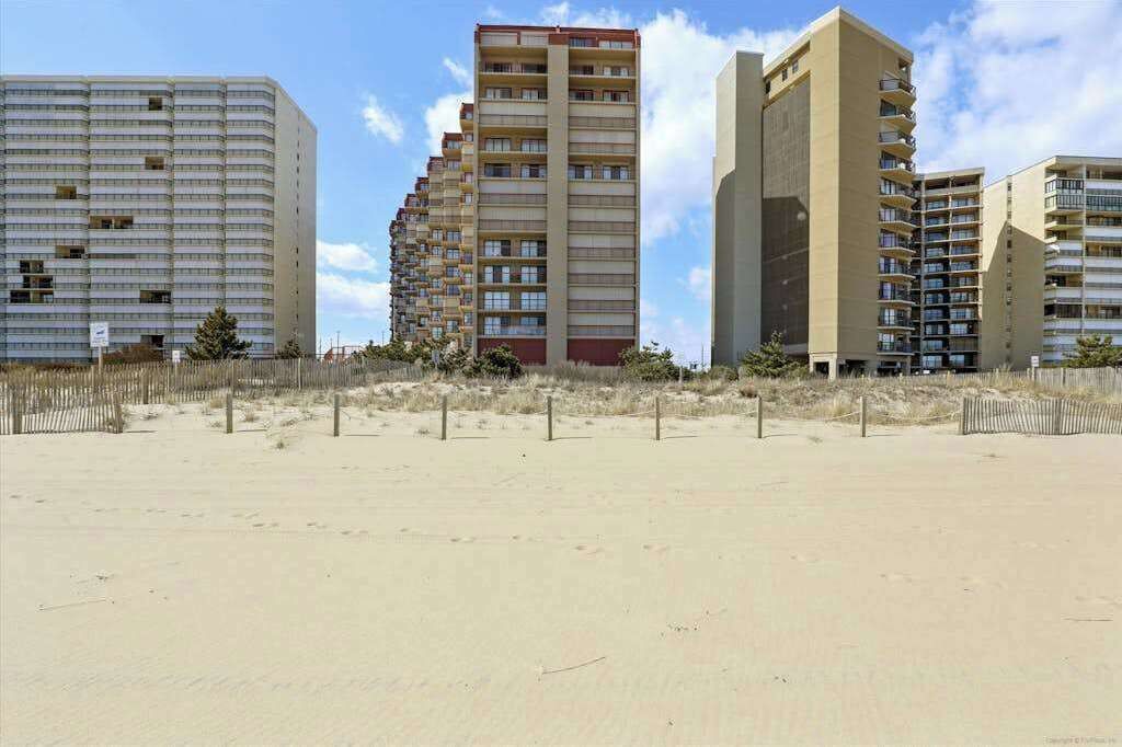 A beachfront hotel with multiple high-rise buildings, sandy beach in front, and a clear sky.