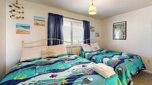Ein Schlafzimmer mit zwei Betten, einem Fenster mit Vorhängen und Wandbildern.