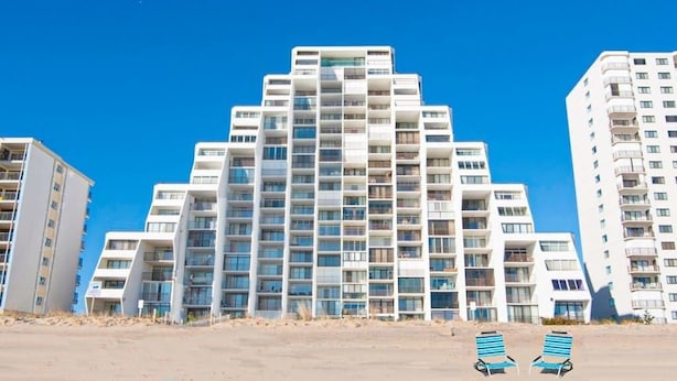 Un hôtel à plusieurs étages doté d’une architecture moderne, avec des balcons et de grandes fenêtres.
