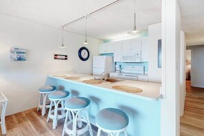 Eine moderne Küche mit weißen Schränken, einer blauen Arbeitsplatte und vier Barhocker.