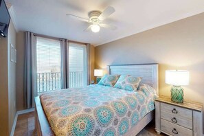 Un dormitorio con cama, mesitas de noche, ventilador de techo y ventana con persianas.