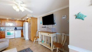 A kitchen with wooden cabinets, a refrigerator, a microwave, and a ceiling fan. - Polynesian 309 (Ocean City)