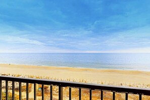 A beach view with a wooden railing, sandy beach, and ocean. - Bright, oceanfront condo with balcony, AC, laundry & outdoor pool (Ocean City)