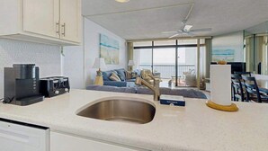 Een moderne keuken met een ingebouwde gootsteen, een koffiezetapparaat en een eethoek met een tafel en stoelen.