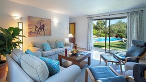 Uma sala de estar com sofá, poltronas, mesa de centro e um quadro.