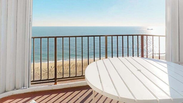 Un balcon avec vue sur l’océan et une table blanche.