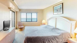 Ein Hotelzimmer mit Bett, Fernseher, Sessel, Fenster mit Aussicht und einem Bild an der Wand.
