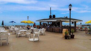 Ein Außenbereich mit Tischen, Stühlen und einer Bar, mit Blick auf das Meer.