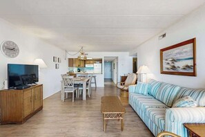 A living room with a television, sofa, and dining area. - Purnell House 402 (Ocean City)