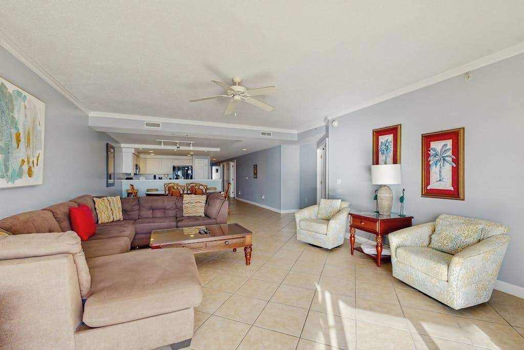 A spacious living room with a large sectional sofa, a coffee table, a side table, and a ceiling fan.