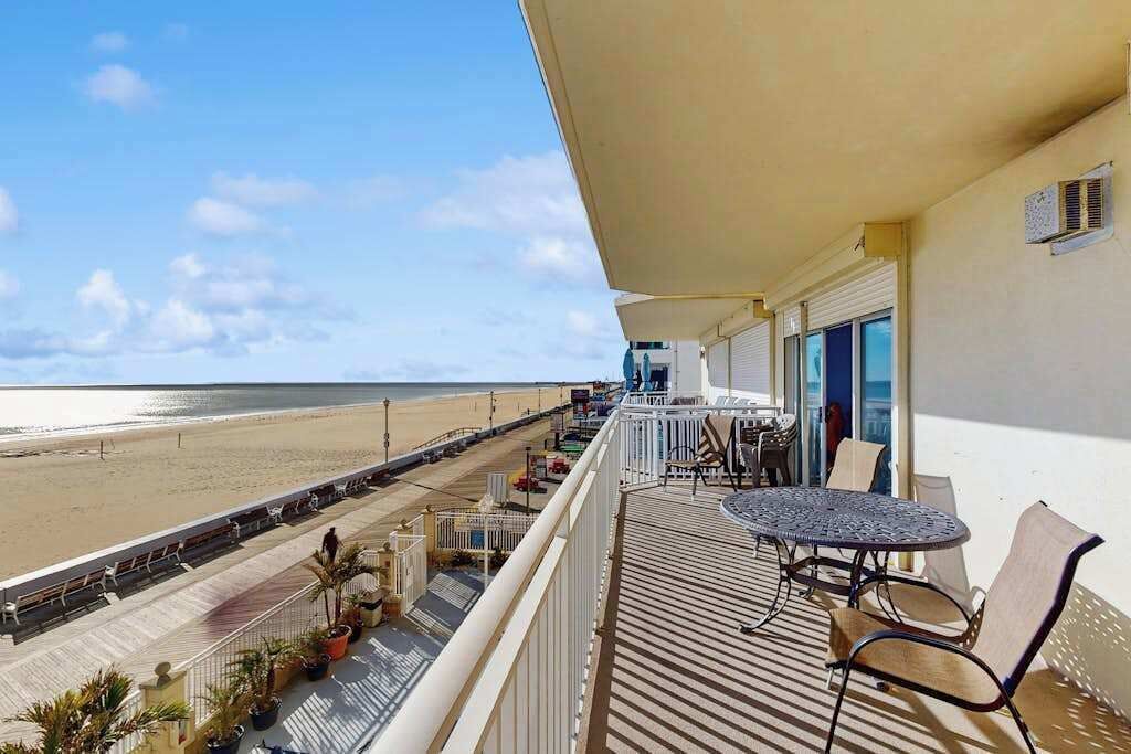Een balkon met een tafel en stoelen, met uitzicht op een strand.