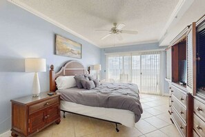 A bedroom with a bed, nightstand, dresser, ceiling fan, and a window with blinds. - Lovely beachfront condo with ocean view, pool, balcony, fireplace, AC, & W/D (Ocean City)