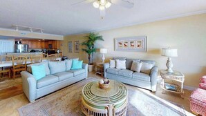 A living room with two sofas, a coffee table, a ceiling fan, and a kitchen in the background. - Incredible Beachfront Condo w/Private Balcony, Fireplace, A/C, & Shared Pool (Ocean City)