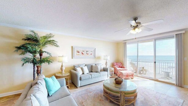 A living room with a sofa, a round coffee table, a ceiling fan, and a large window with a view. - Incredible Beachfront Condo w/Private Balcony, Fireplace, A/C, & Shared Pool (Ocean City)