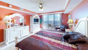 A bedroom with a bed, dresser, and a balcony with a chair. - Incredible Beachfront Condo w/Private Balcony, Fireplace, A/C, & Shared Pool (Ocean City)