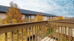 A wooden deck with a view of a building and autumn trees. - Marlin Cove 405 (Ocean City)