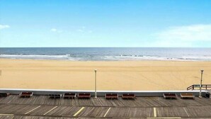 A beach view from a balcony with wooden railings and benches. - Beachfront Condo w/Private Balcony, Beach Views, Washer/Dryer, Central A/C (Ocean City)