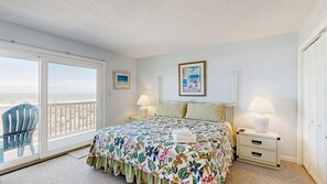 A bedroom with a bed, two bedside tables, a chair, a balcony, and a painting on the wall. - Ocean Club 4007 (Ocean City)