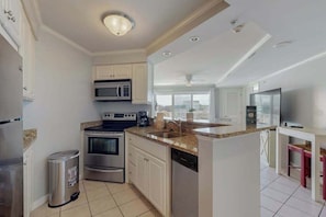 A modern kitchen with white cabinets, stainless steel appliances, and a central island. - Makai 108 (Ocean City)
