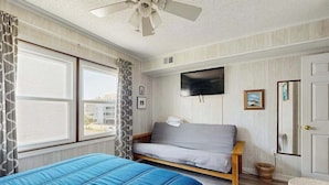 A room with a bed, a sofa, a television, and a window with curtains. - Well-Equipped Beach Condo near the Ocean w/Private Balcony, Central A/C, W/D (Ocean City)