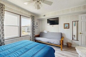 Ein Zimmer mit einem Bett, einem Sofa, einem Fernseher und einem Vorhangfenster.