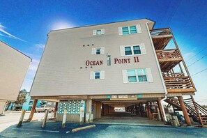 Ein mehrgeschossiges Gebäude mit der Beschilderung 'Ocean Point II', einem überdachten Eingang und einer Holztreppe auf der rechten Seite.