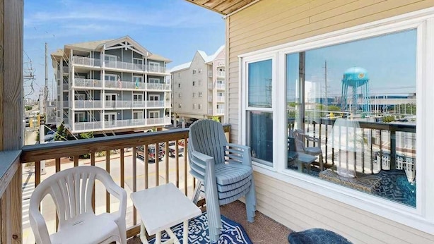 A balcony with a view of neighboring buildings, a chair, a table, and a patterned rug. - Well-Equipped Beach Condo near the Ocean w/Private Balcony, Central A/C, W/D (Ocean City)