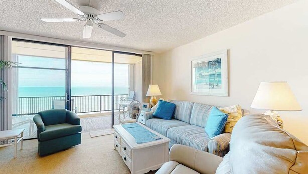 Ein Hotelzimmer mit Balkon, Deckenventilator, Sofa, Couchtisch und Lampe.