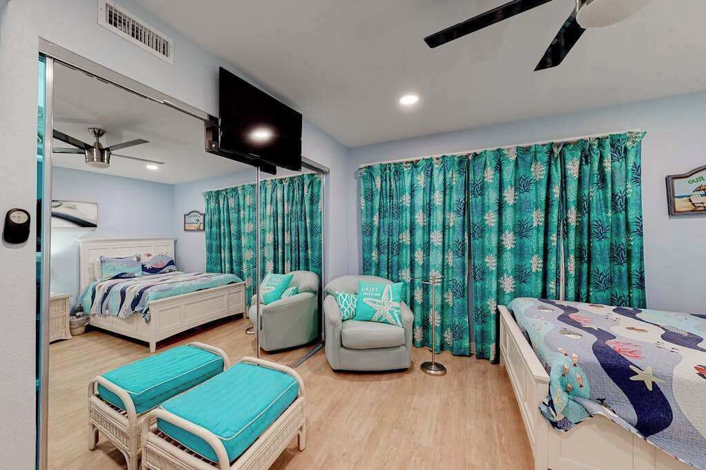 A bedroom with a bed, two bedside tables, a chair, a TV, and curtains.