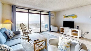 Et moderne hotelværelse med balkon, sofa, sofabord, TV-møbel og en fiskedekoration.