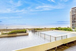 A rooftop deck with a view of the beach and ocean. - Beachfront condo with amazing views, balcony, & outdoor pool (Ocean City)