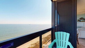 A balcony with a view of the beach and ocean, a turquoise chair, and a sign indicating 'Common Elements.' - Budget-friendly beachfront condo with balcony, pools, gym & sauna (Ocean City)