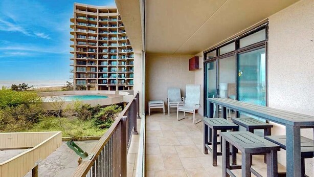 Ein Balkon mit Pool, im Hintergrund ein Hochhaus und ein klarer Himmel.
