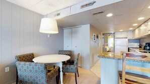 A modern kitchen with a white island, grey walls, and patterned chairs. - Grandview 203 (Ocean City)