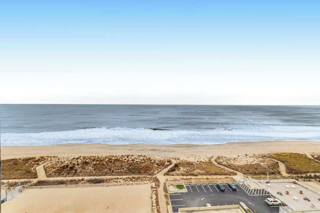 A beach view with a parking lot and a building with a flat roof.