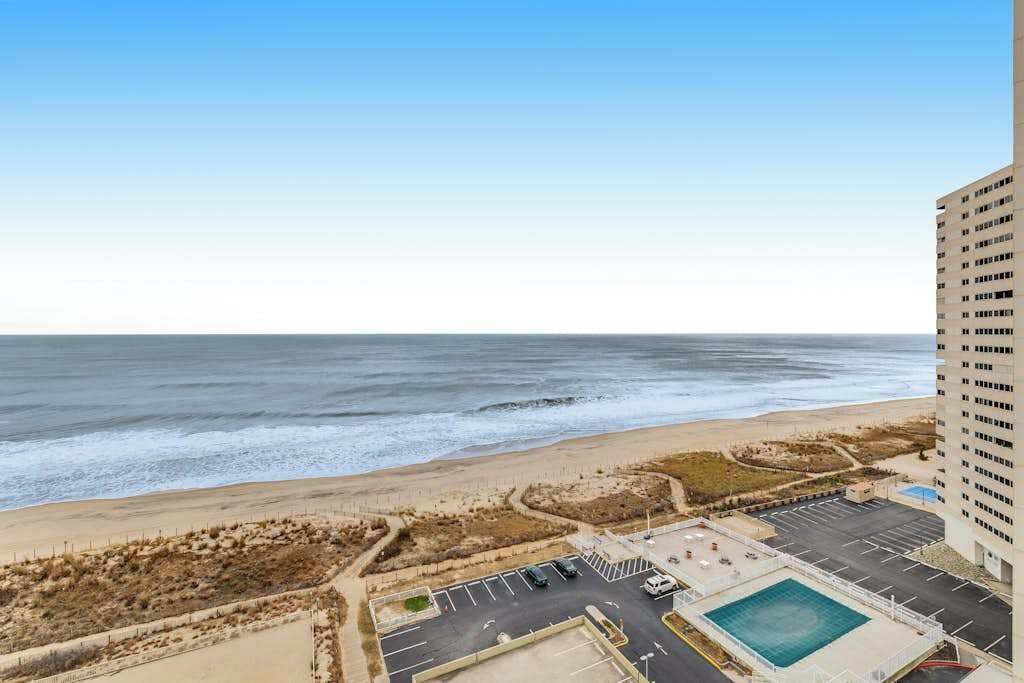 A high-rise hotel with a view of the ocean and a pool area.