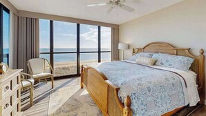 A bedroom with a large window, a bed, a chair, and a ceiling fan. - Convenient beachfront condo with balcony, pools, tennis, gym & central AC (Ocean City)