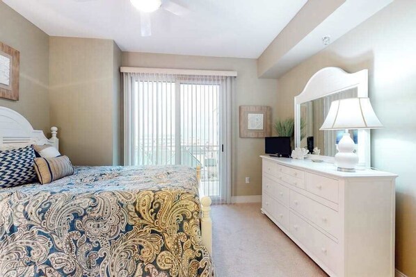 A bedroom with a bed, a dresser, a mirror, and a window with blinds. - Gateway Grand 301 (Ocean City)